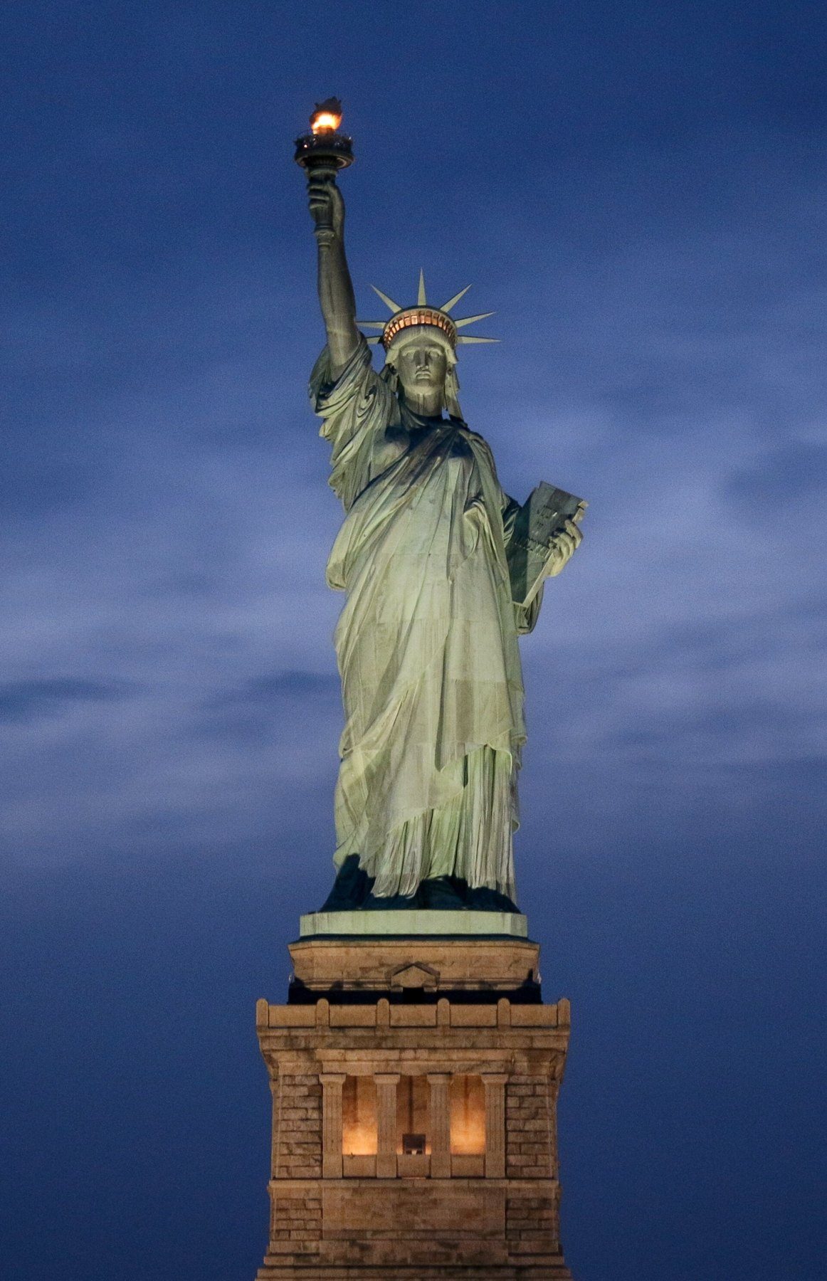 The Statue of Liberty at dusk against a deep blue sky