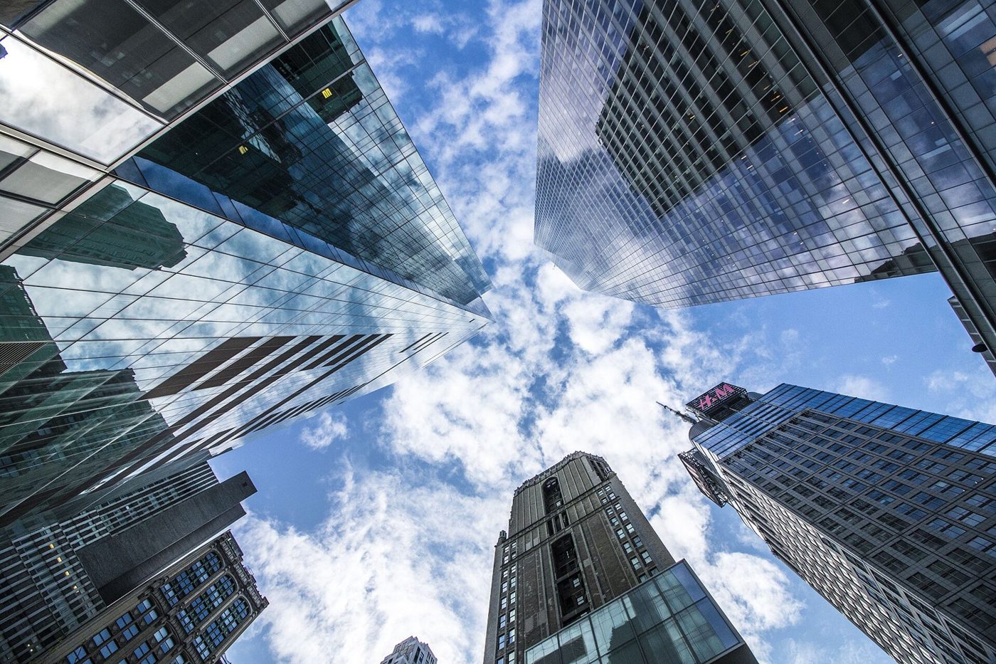 Looking up at glass skyscrapers in Manhattan against a cloudy blue sky